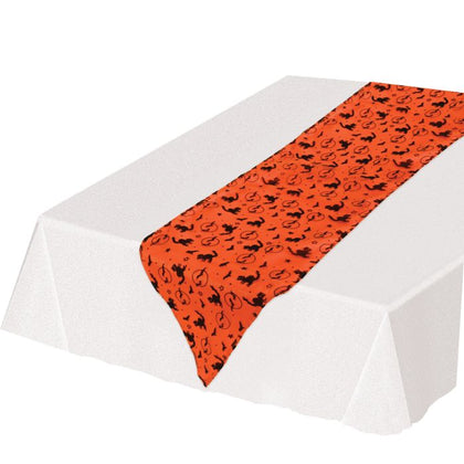 Table runner with black cat pattern on an orange background, placed on a white tablecloth.
