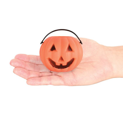 Hand holding a small orange pumpkin-shaped bucket with a black handle on a white background