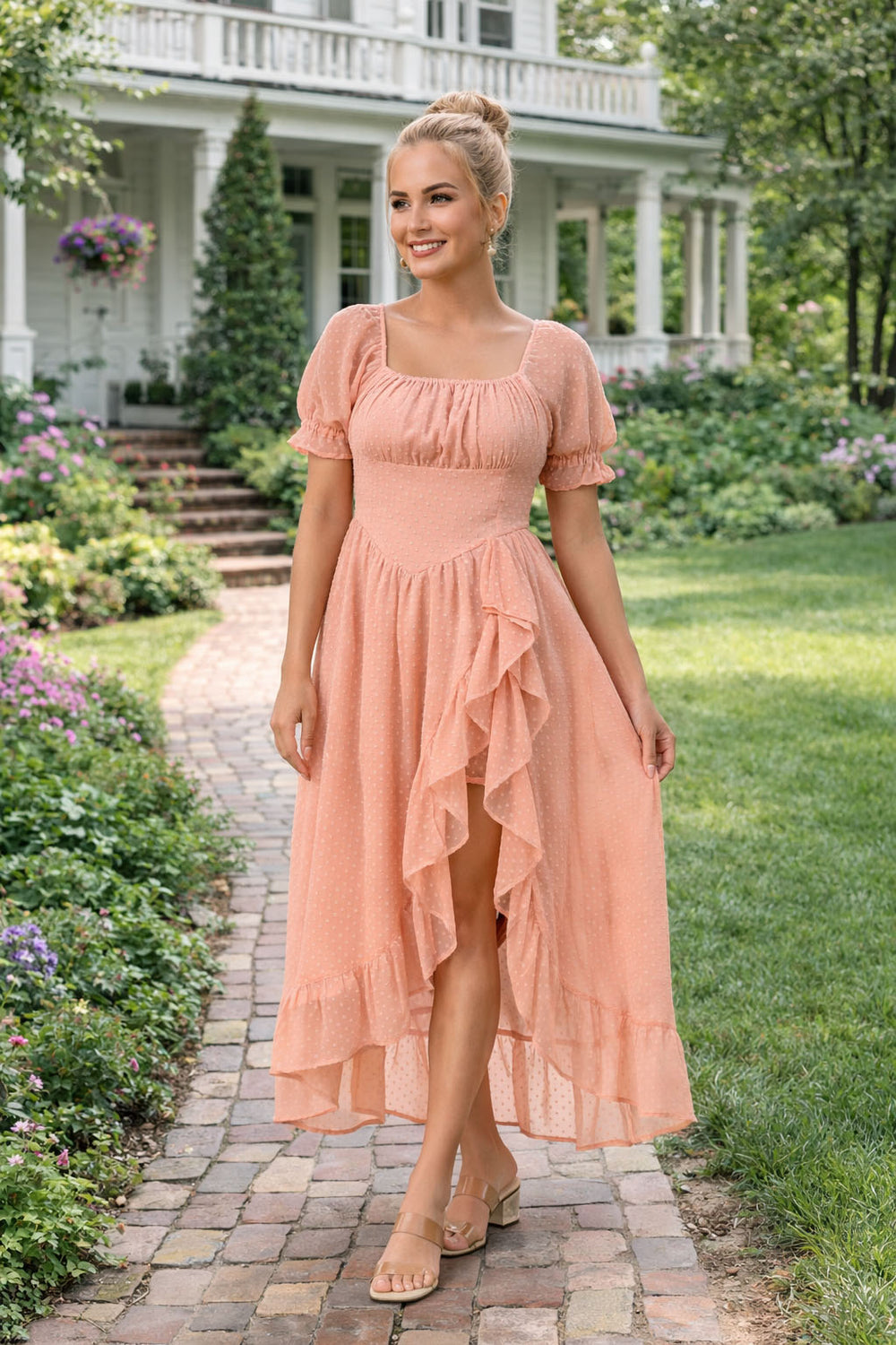 Woman in a peach dress standing in a garden path with a house in the background