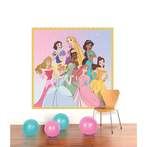 Framed poster of Disney princesses on a wall with colorful balloons on the floor.