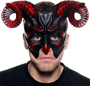 A man wearing a black and red horned mask, photographed against a plain white background.