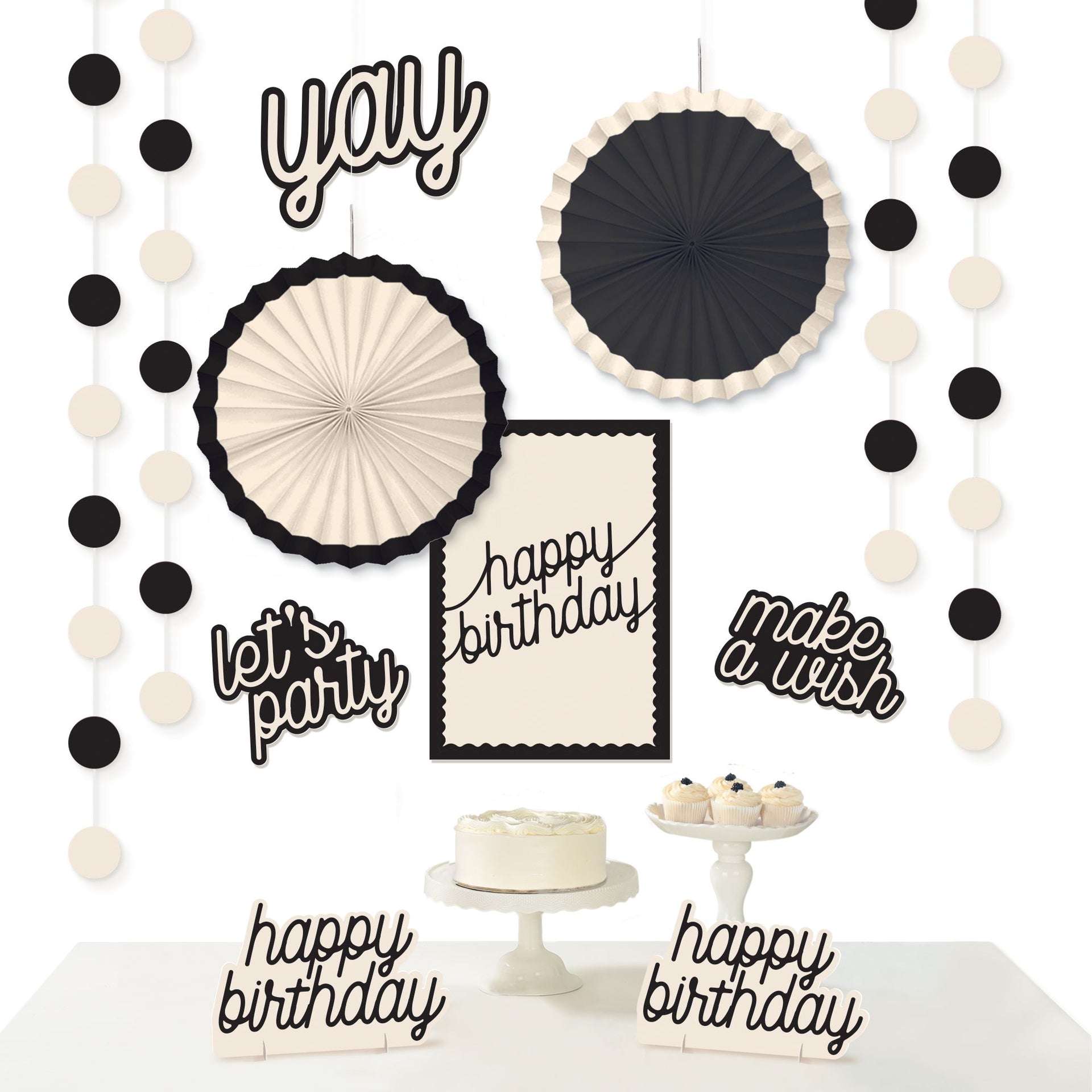 Black and white birthday party decorations with text and cake on a table.
