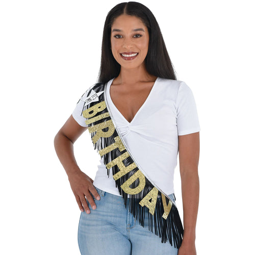 Woman wearing a 'Birthday' sash with gold and black design on a white background