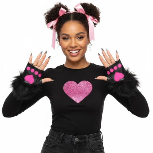 A woman modeling a black long-sleeve top with a glittery pink heart on the chest, black faux-fur trimmed cuffs, and matching black fingerless gloves with pink paw prints. She has pink hair bows in her hair, posed against a solid white background.