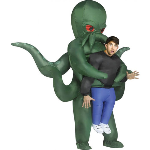 A man wearing a green inflatable Cthulhu costume, with tentacles and red eyes, carrying him against his back. The costume includes a black long-sleeve shirt, blue pants, and white sneakers, shown against a plain white background.