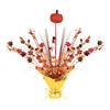 Decorative centerpiece with autumn leaves and a pumpkin on top, wrapped in gold paper.