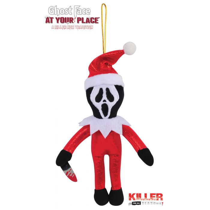 A Ghost Face plush elf ornament from the movie 'A Dollar Night Tradition' hanging from a gold string. The plush features Ghost Face's iconic black-and-white mask, a red and white Santa suit, and holds a bloody knife.