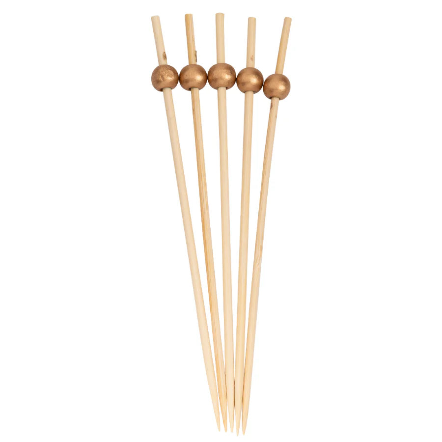 Set of wooden skewers with gold beads on a white background