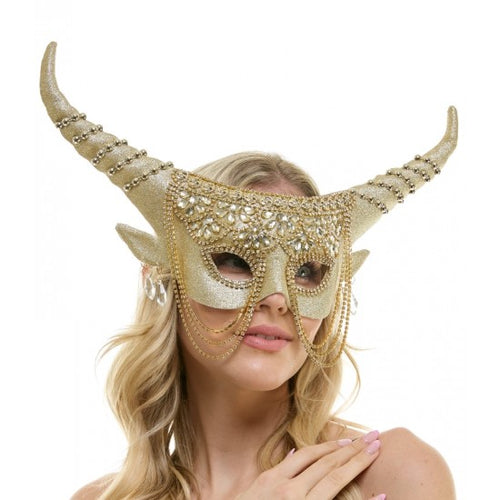A woman wearing a glittery gold masquerade mask with long curved horns, jeweled embellishments, and dangling beaded chains, photographed against a plain white background.