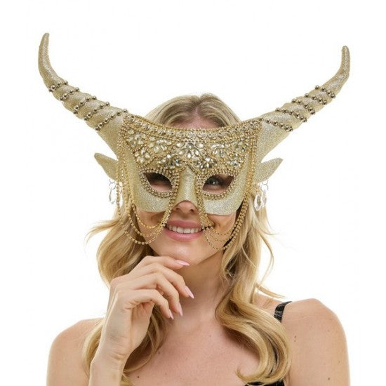 A woman wearing a decorative gold horned masquerade mask with rhinestone embellishments and long curved horns, photographed against a plain white background.