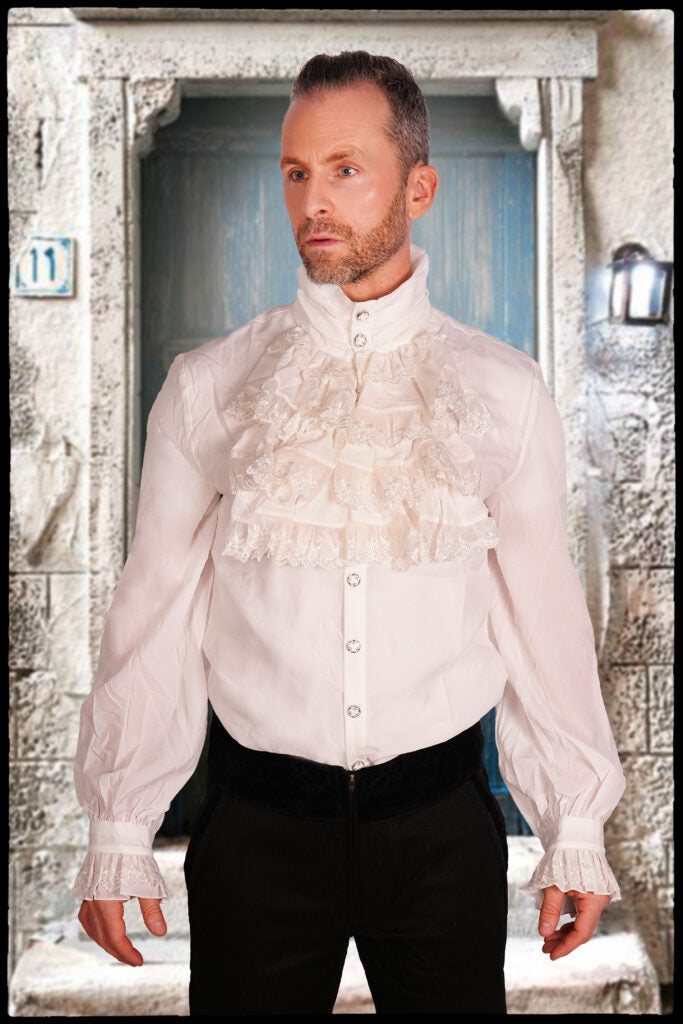 Man wearing a white blouse with ruffled collar and cuffs in an outdoor setting.