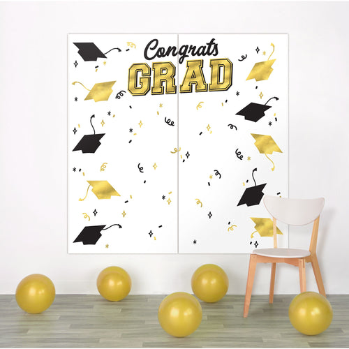 Graduation-themed wall decoration with 'Congrats Grad' text and caps on a white wall.