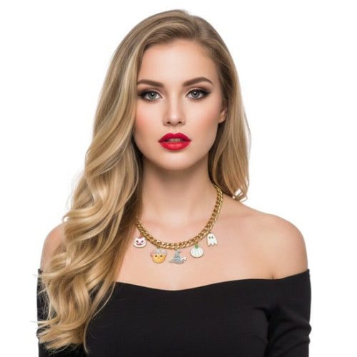 A blonde woman with long wavy hair models a gold chain necklace with small colorful enamel charms, including a ghost, a smiling face, and a pumpkin, against a plain white background.