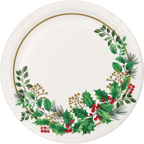 A round white paper plate decorated with a festive wreath design featuring green holly leaves, red berries, pine needles, and a thin gold rim.