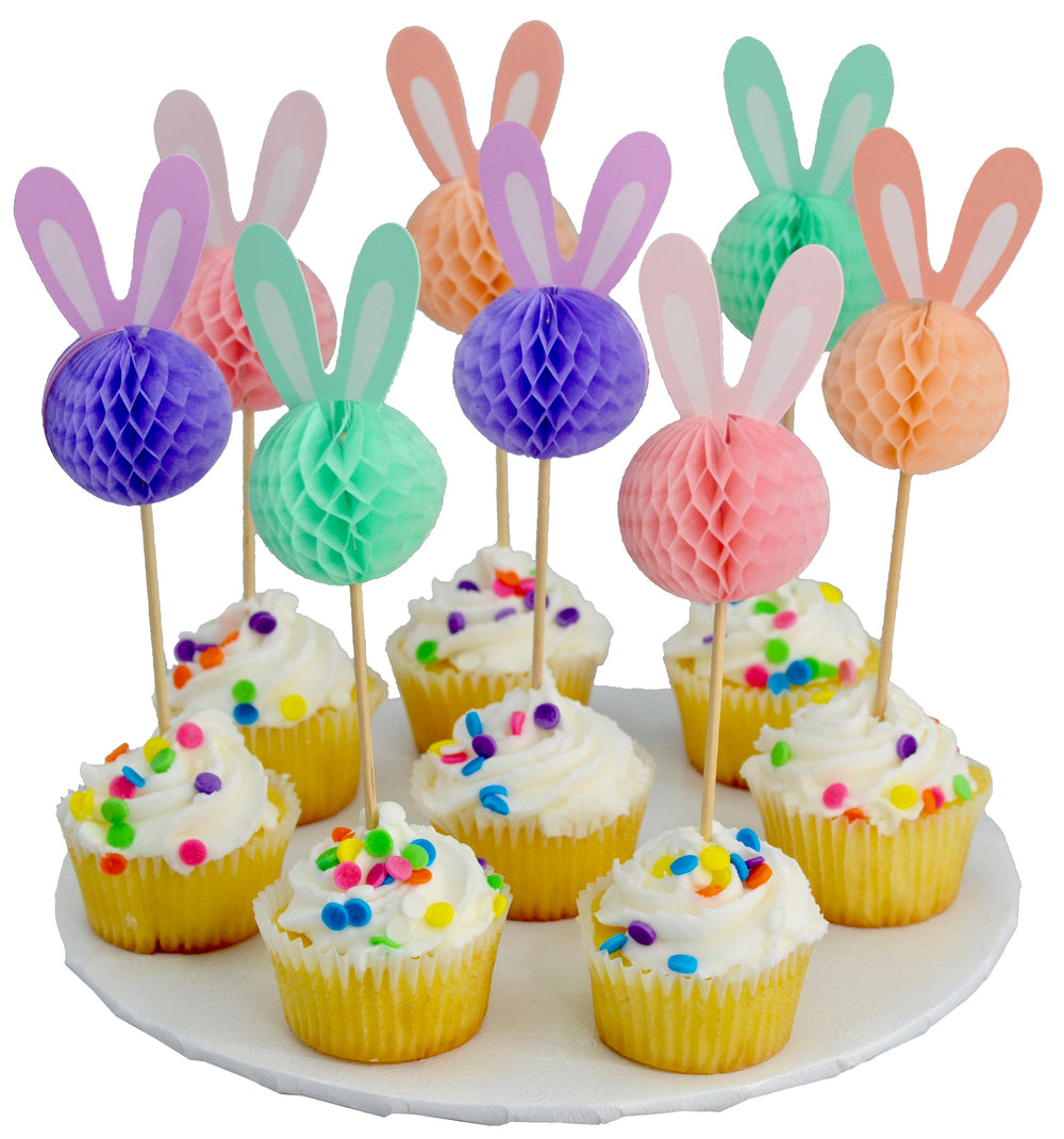 Decorative bunny ears on cupcake sticks with colorful honeycomb balls over cupcakes on a white plate.