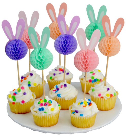 Decorative bunny ears on cupcake sticks with colorful honeycomb balls over cupcakes on a white plate.