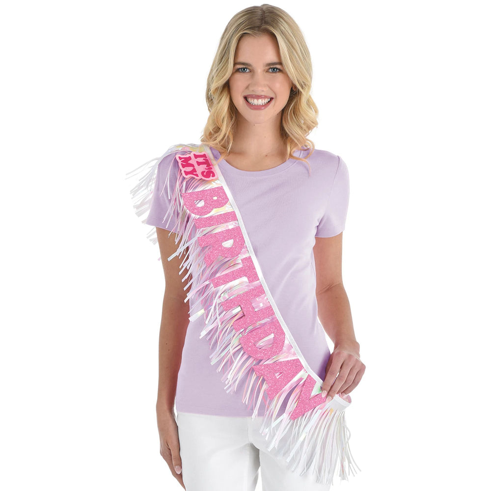 Woman wearing a 'Happy Birthday' sash with fringe on a white background