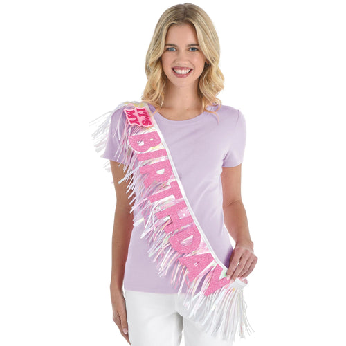 Woman wearing a 'Happy Birthday' sash with fringe on a white background