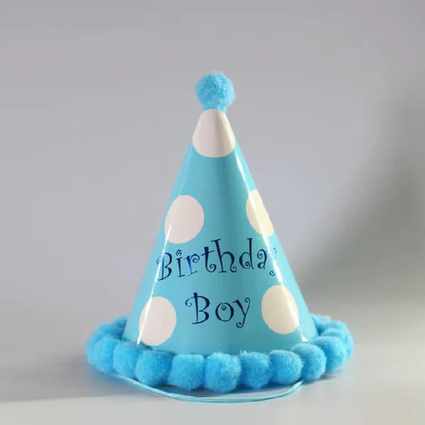 Blue birthday hat with white polka dots and 'Birthday Boy' text on a gray background
