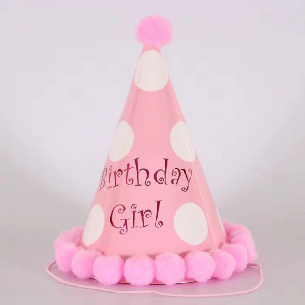 Pink birthday hat with white polka dots and pink pom-poms on a light gray background