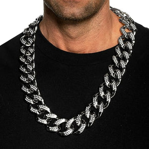 Man wearing a large silver chain necklace on a black background