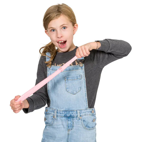 Child wearing denim overalls holding a pink rubber band against a white background