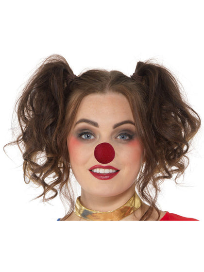 Person with brown hair styled in pigtails and a red clown nose on a white background