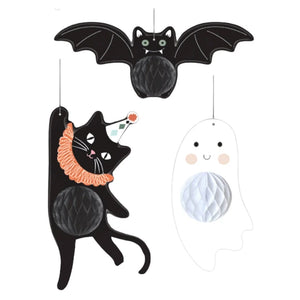 Three Halloween-themed hanging decorations on a plain white background: a black bat at the top, a black cat wearing an orange ruffled collar and party hat on the left, and a white ghost outline with a white honeycomb belly on the right.