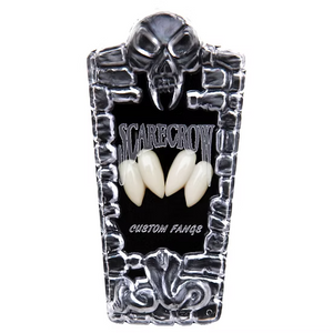 A coffin-shaped display case for custom teeth or fangs, featuring a skull at the top, a black center panel with the words 'SCARECROW' and 'CUSTOM FANGS,' and three cream-colored fangs displayed in the middle, all on a white background.