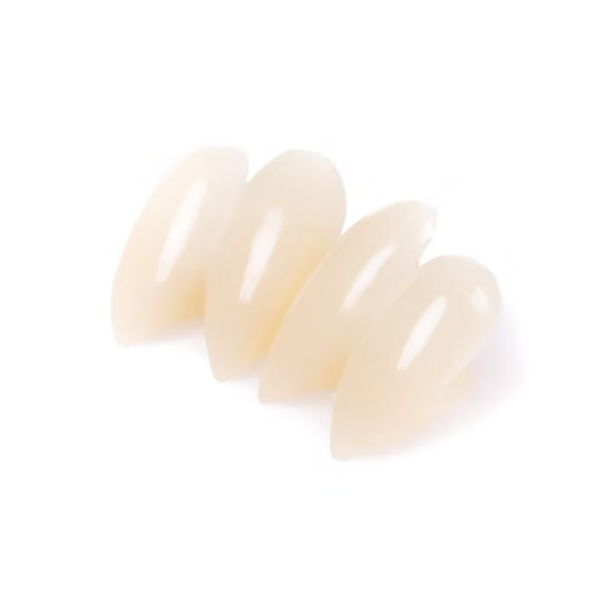 Four glossy, almond-shaped false nail tips in a translucent nude beige color, arranged diagonally on a plain white background.