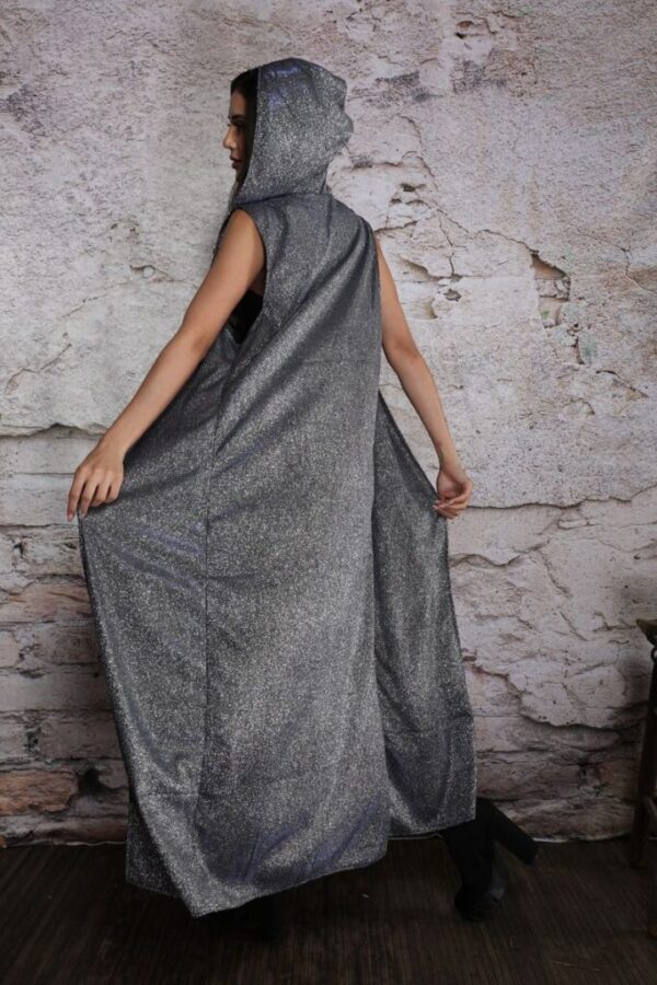 Person wearing a long, dark gray hooded garment against a textured stone wall.