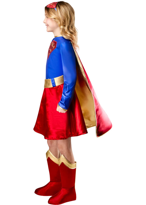 Child wearing a superhero costume with a red cape and boots on a white background