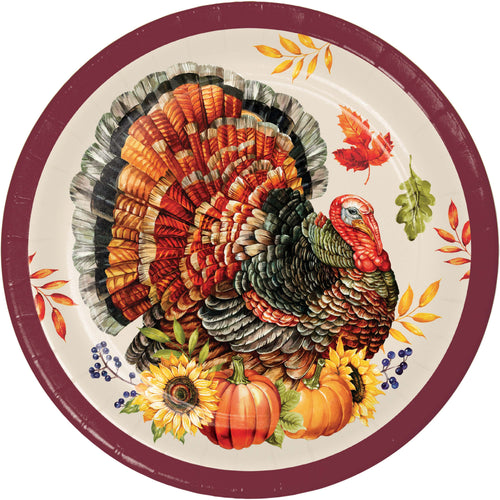 A round paper plate featuring a detailed illustration of a turkey with autumn leaves, pumpkins, and sunflowers, set against a cream background with a dark red rim.