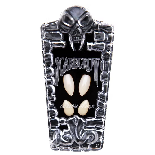 A coffin-shaped Halloween mask or plaque featuring a black background, silver skull and stone-like border details, and two off-white pointed teeth-like cutouts in the center. The word 'SCARECROW' is printed across the top.