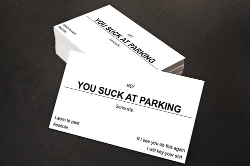 Two business cards with humorous text on a dark surface