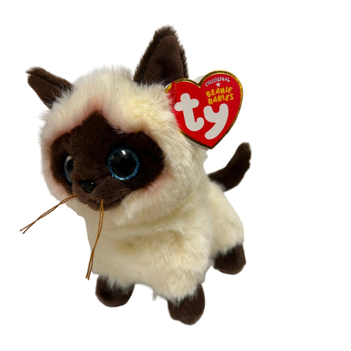 A Ty Beanie Babies Siamese Doodle plush toy sitting on a desk with papers in the background.