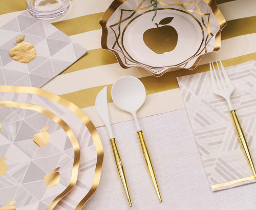 Dinnerware set with gold and white accents on a striped tablecloth