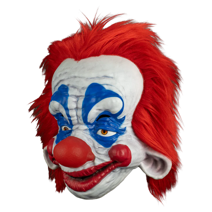 Clown mask with red hair, white face, and blue face paint on a white background
